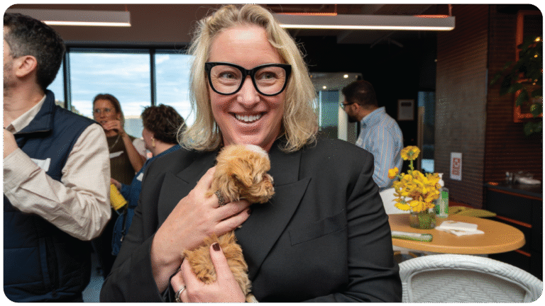 Attendee smiling while holding a puppy at the PetAds Unleashed event in Melbourne, highlighting the energy and pet-first spirit of the retail media community.